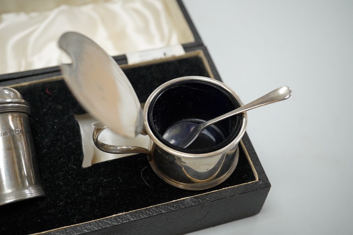 A George V silver tall cream jug, Birmingham, 1930, 17.2cm, a 1950's silver small mug, London, 1955 and a cased 1930's silver three piece condiment set.